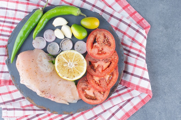 Free photo uncooked chicken fillet on wooden board with vegetables.