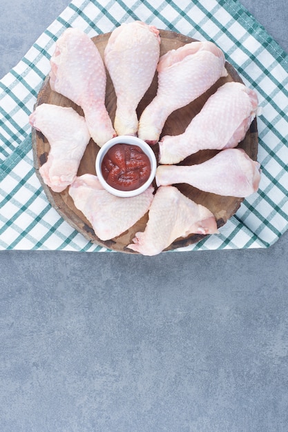 Free photo uncooked chicken legs and wings on wood piece.