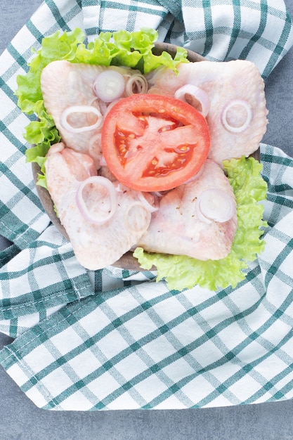 Uncooked chicken wings on wooden board.