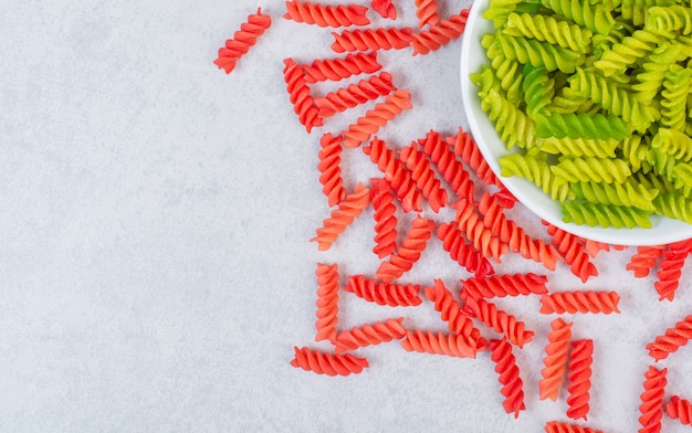 Uncooked colorful dry spiral pasta on a stone.