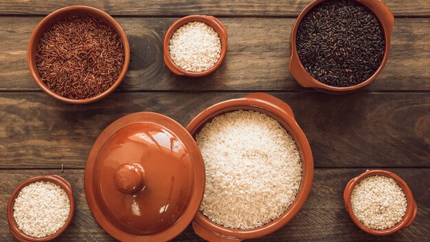 Uncooked different type of rice grains on wooden plank