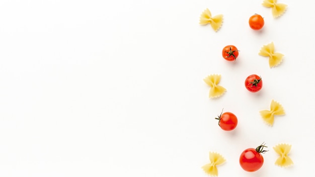 Uncooked farfalle arrangement with tomatoes with copy space