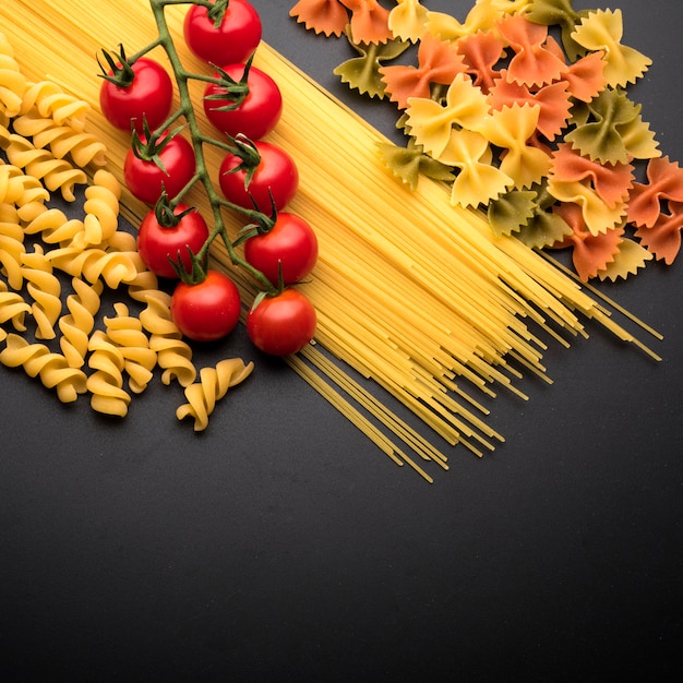 Uncooked italian pasta and cherry tomatoes over kitchen worktop