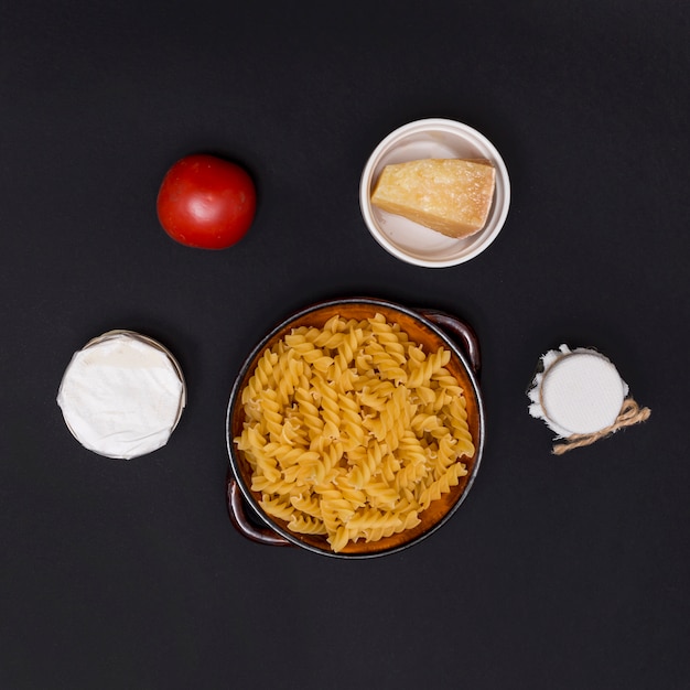 Uncooked italian twisted fusilli pasta and ingredient over kitchen counter