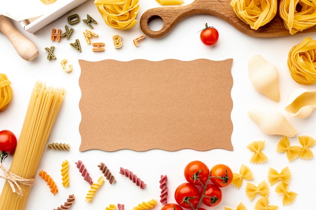 Free photo uncooked pasta mix tomatoes and hard cheese with cardboard mock-up