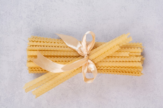 Free Photo uncooked pasta tied with ribbon on white surface