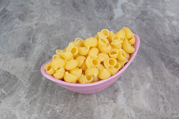 Uncooked pastas in a pink metallic platter on the marble