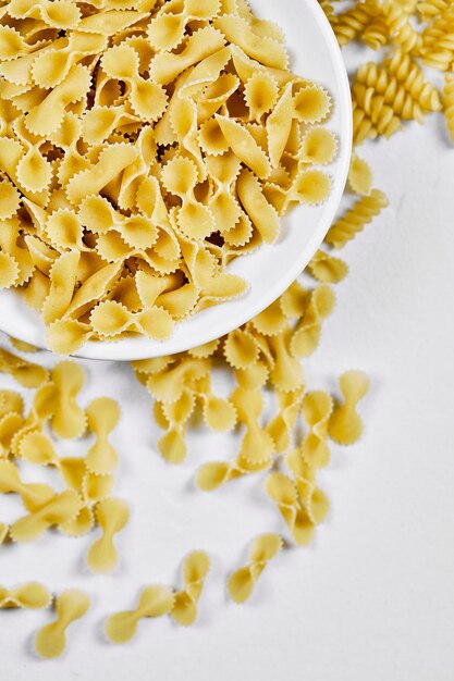 Uncooked pastas on white table.