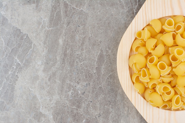 Uncooked pastas in a wooden platter on the marble. 