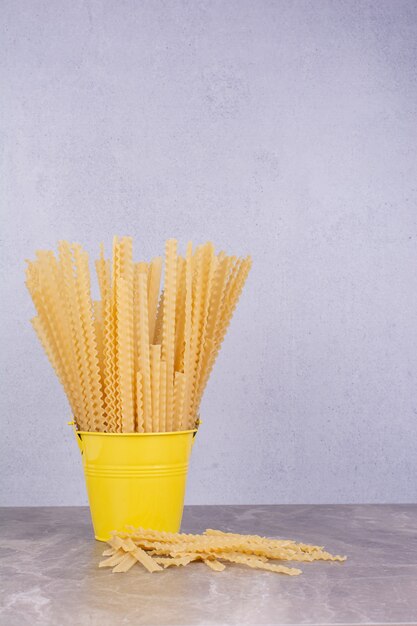 Uncooked pastas in a yellow metallic container bucket