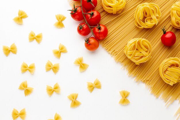 Uncooked spaghetti tagliatelle farfalle and tomatoes