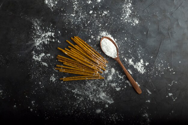 Uncooked spaghetties with flour in a wooden spoon