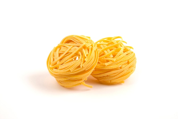 Uncooked tagliatelle nests on white.