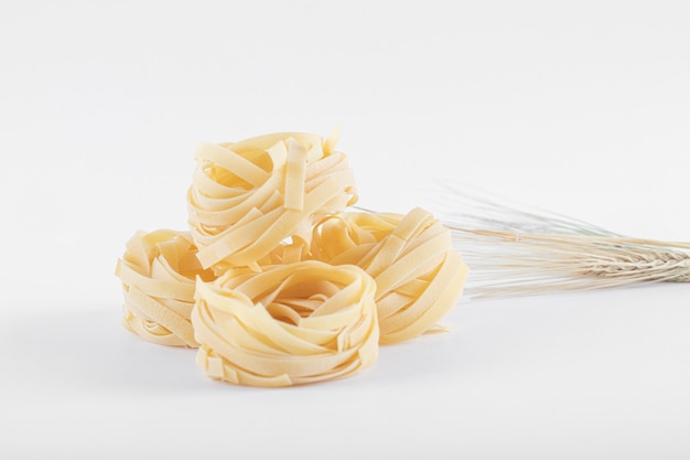 Free photo uncooked tagliatelle nests on white.