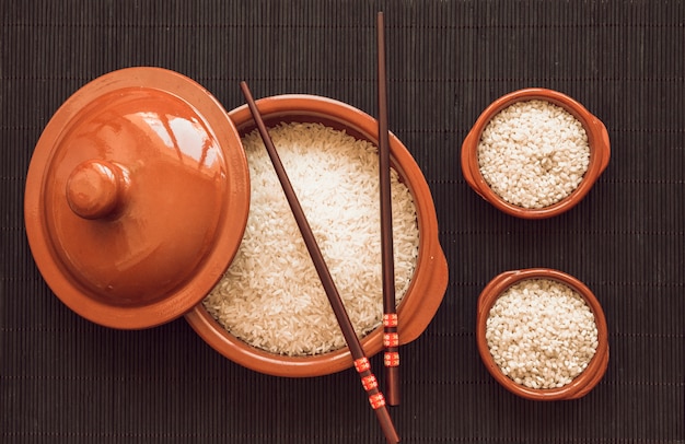 Uncooked white rice grains pot and two bowls on placemat