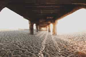 Free photo underneath the wooden bridge at sandy beach