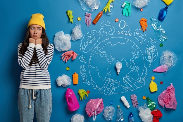 Free photo unhappy korean woman participates in ecological project, looks sadly at all plastic garbage, concerned by serious environmental problem