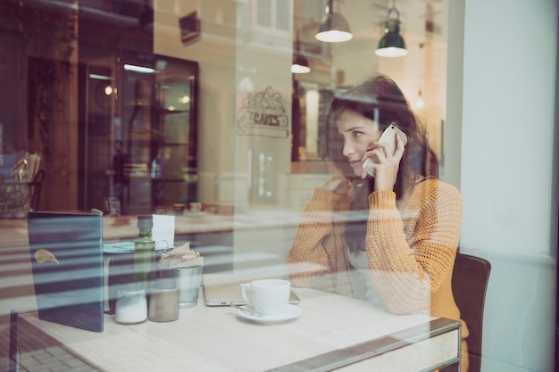 Free photo unhappy woman speaking on phone in cafe