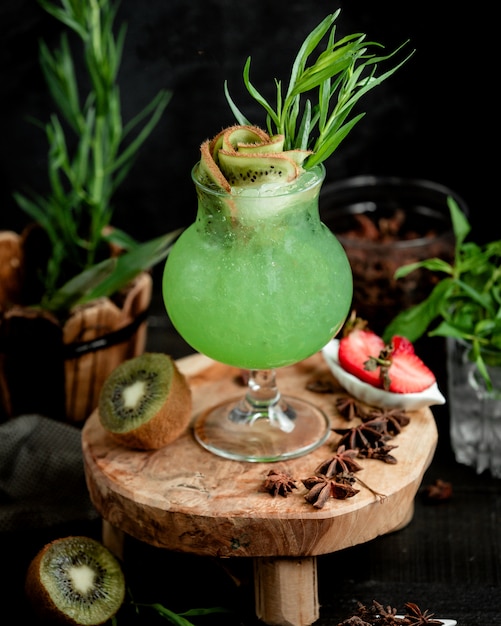 A unique glass of kiwifruit cocktail garnished with kiwifruit slices and tarragon