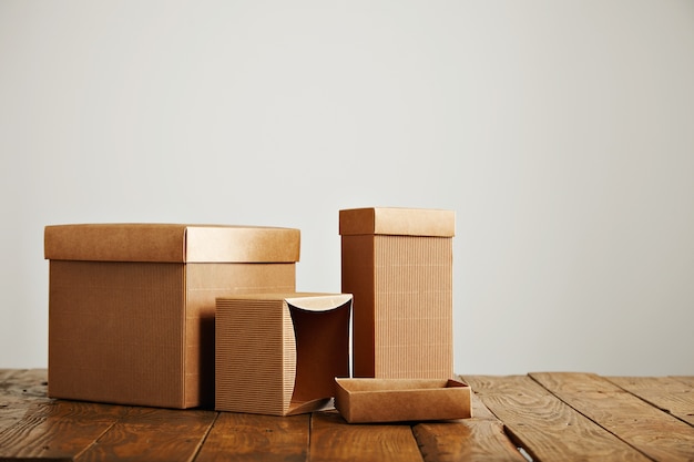 Free photo unlabeled similar boxes of different shapes and sizes on an uneven wooden table isolated on white