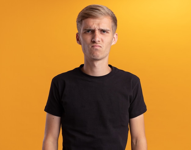 Free photo unpleased looking at front young handsome guy wearing black shirt isolated on yellow wall