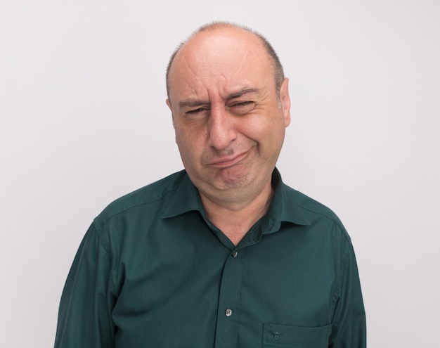 Unpleased middle-aged man wearing green t-shirt isolated on white wall