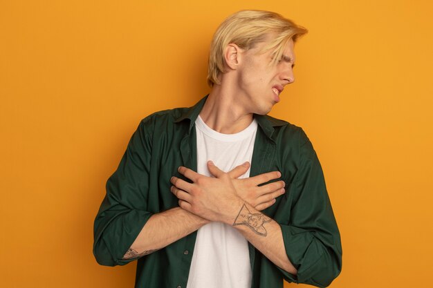 Unpleased with closed eyes young blonde guy wearing green t-shirt crossing hands