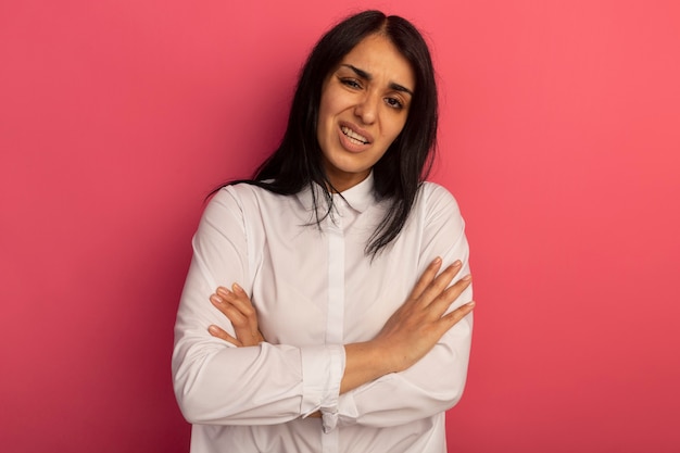 Unpleased young beautiful girl wearing white t-shirt crossing hands isolated on pink