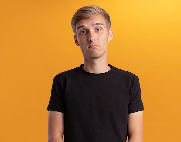 Free photo unpleased  young handsome guy wearing black shirt isolated on yellow wall