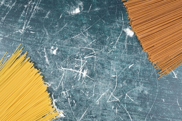 Unprepared pasta bunch of whole grain spaghetti on marble background