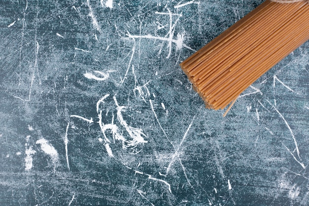 Unprepared pasta bunch of whole grain spaghetti tied with rope on marble backgroundto