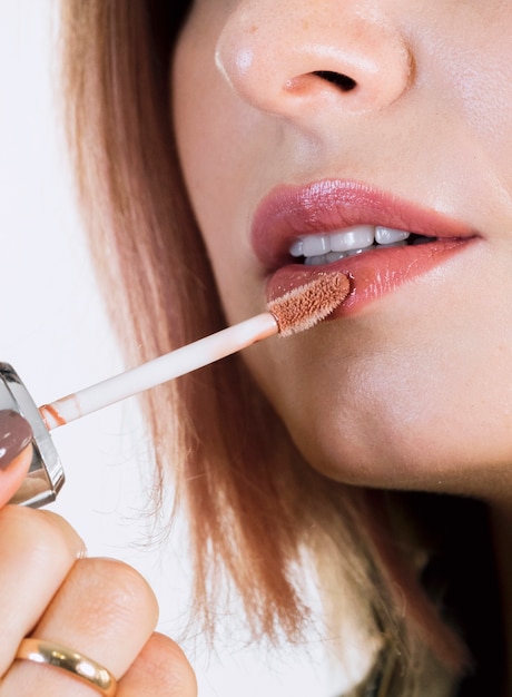 Free photo unrecognisable woman applying lipstick