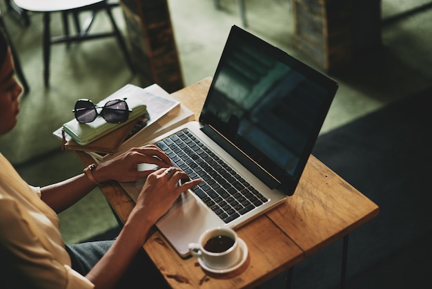 Free photo unrecognizable asian woman sitting in cafe and working on laptop