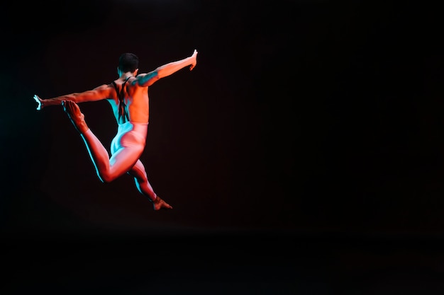 Free photo unrecognizable ballet dancer jumping with spread arms and doing splits