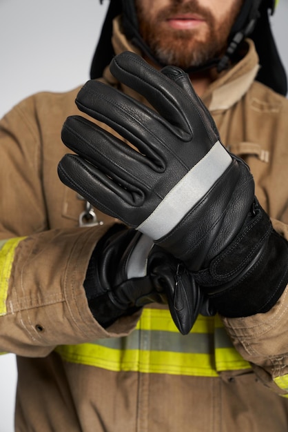 Unrecognizable bearded firefighter wearing leather protective gloves