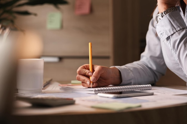 Unrecognizable businesswoman working in the office and writing business plans in her notebook