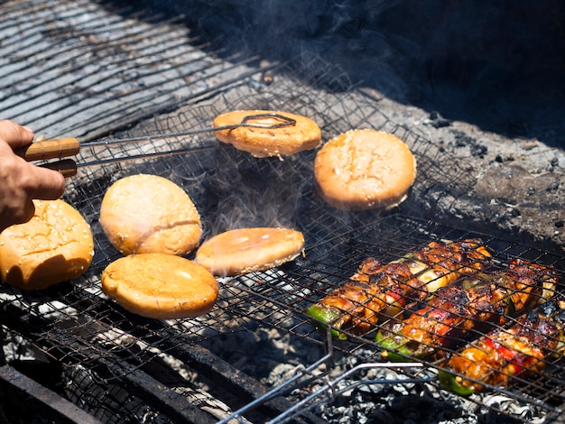 Free photo unrecognizable cook flipping burger buns roasting on grid with tongs