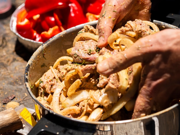 Unrecognizable cook mixing pieces of meat and onion for shashlik
