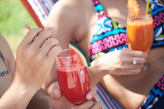 Unrecognizable couple in swimsuits enjoying beverages at luxurious resort