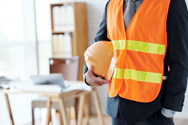 Free photo unrecognizable male construction industry executive posing in safety vest, with hardhat