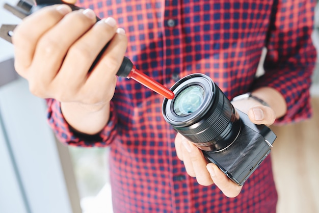 Free Photo unrecognizable male photographer cleaning camera lens with air blower