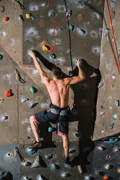 Unrecognizable man climbing wall