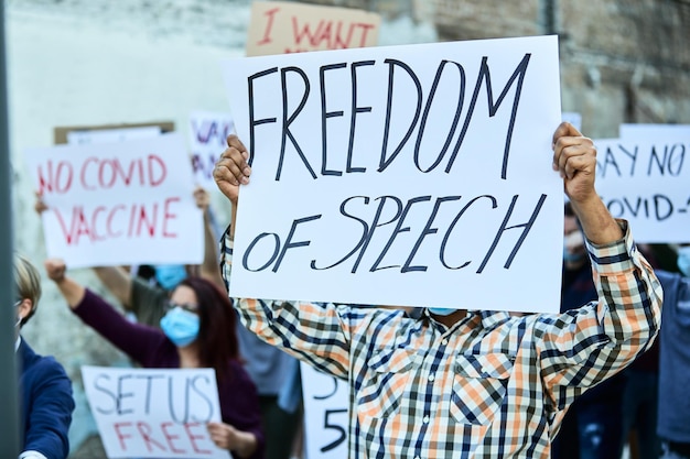 Free photo unrecognizable man with freedom of speech banner marching with group of people on a protest during coronavirus pandemic