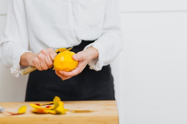 Free photo unrecognizable person peeling fruit