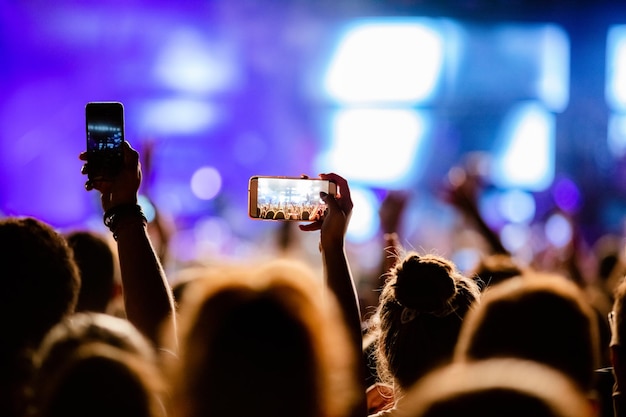 Free Photo unrecognizable person photographing with smart phone stage performers on music festival