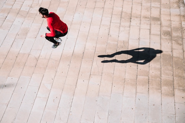 Unrecognizable sportsman jumping on pavement