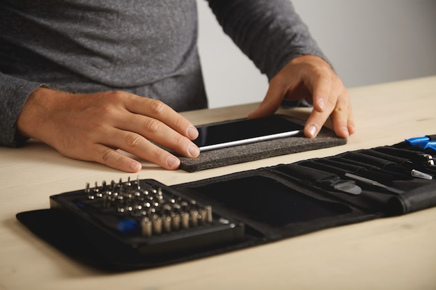 Free photo unrecognizable technician preparing broken smartphone for dissassembling process