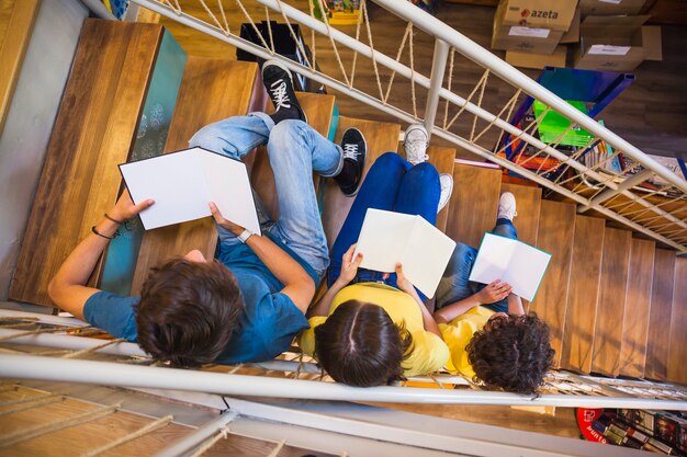 Unrecognizable teenagers reading on staircase