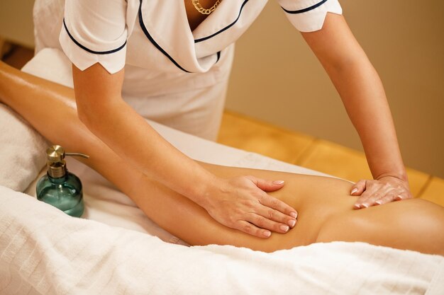 Unrecognizable therapist massaging thighs of a woman at the spa