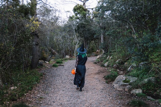 Unrecognizable witch in forest